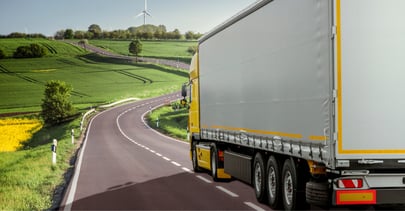 Camion conduisant sur une route près de champs.